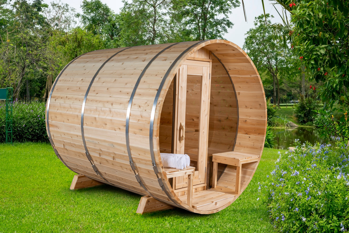 Wooden barrel-shaped sauna in a garden setting with greenery.