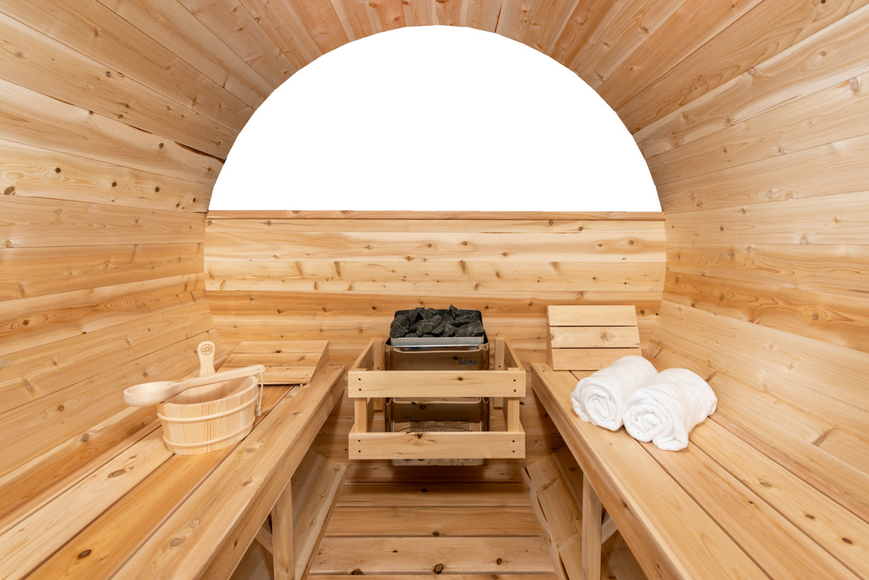 Wooden sauna interior with benches, towels, and a bucket.