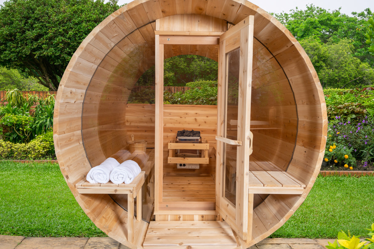 Wooden outdoor sauna with towels inside, surrounded by greenery