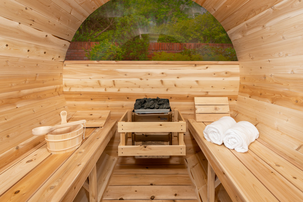 Wooden sauna interior with benches, towels, and a view of trees outside.